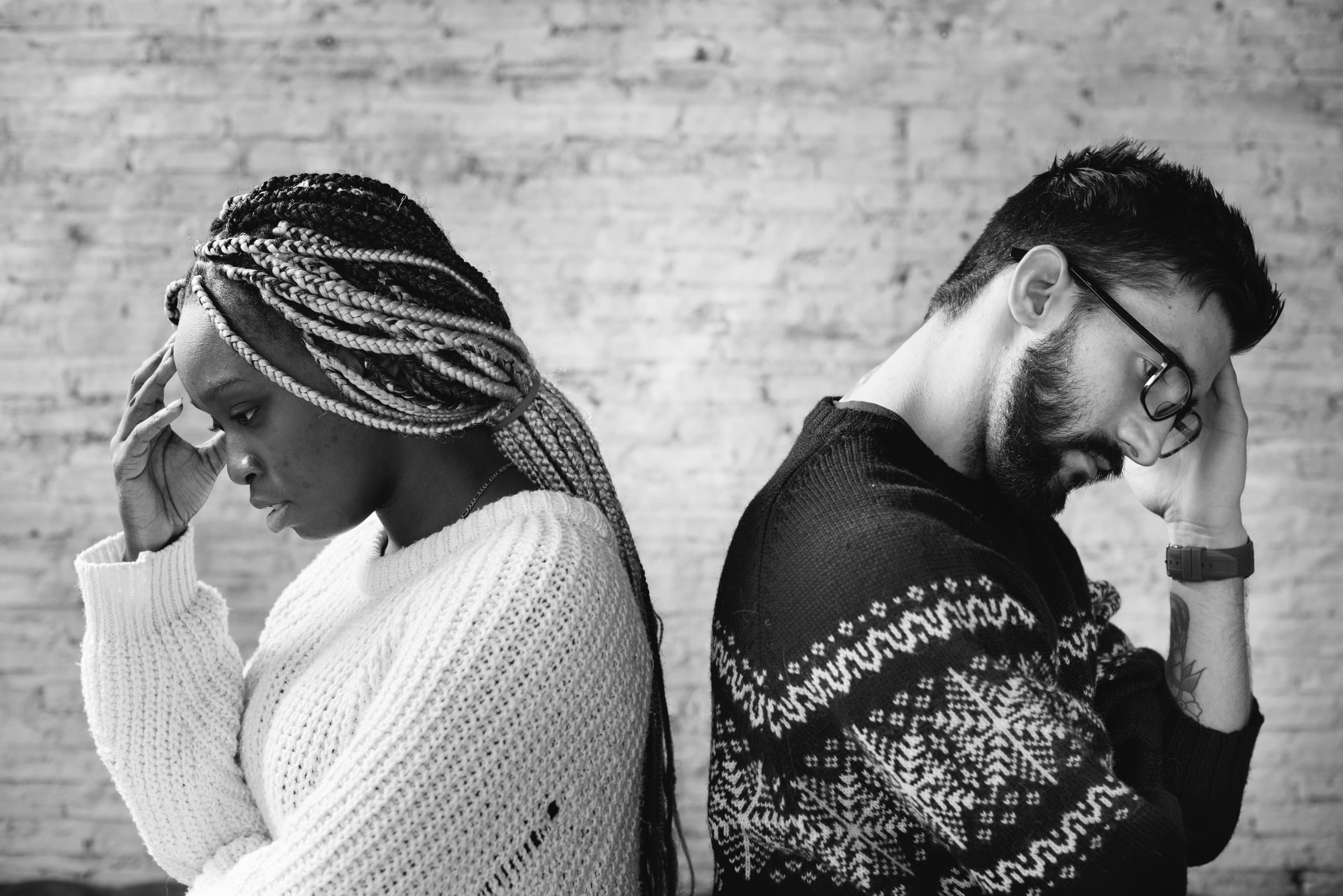 A couple standing back to back, both looking stressed and disconnected