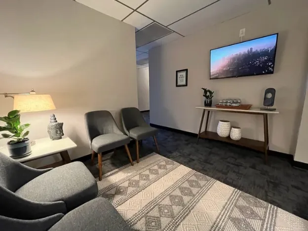 Waiting area with armchairs, a console table, and a wall-mounted screen