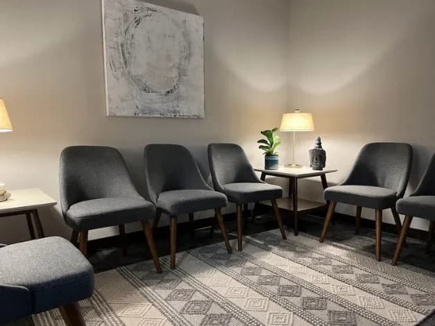 Waiting room with a row of upholstered chairs beneath a framed abstract painting